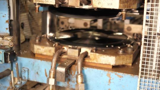 乙烯基唱片压制机在运行，在乙烯基工厂制作音乐唱片