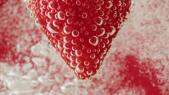 草莓切片在气泡水中冒泡的慢镜头特写
