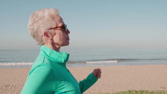 海滩上锻炼的老年妇女视频素材模板下载