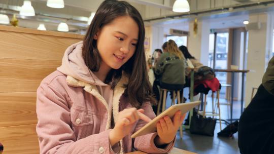 女留学生在学校餐厅使用手机