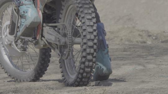 越野摩托车起步泥土和石头从轮子下飞起