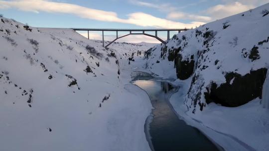 无人机在美丽的风景中飞过冰岛桥下的峡谷