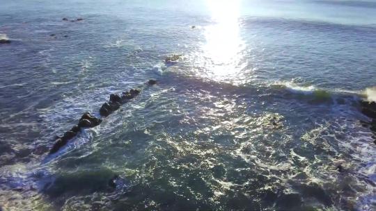 航拍大海海浪拍打礁石太阳光线照射在海面上