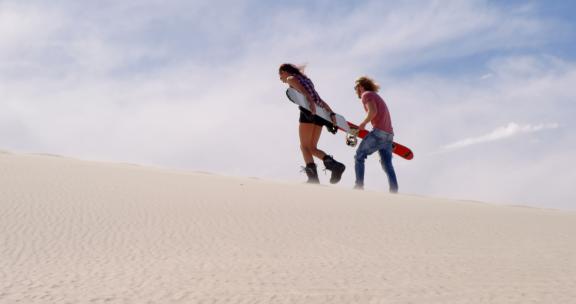 一对夫妇在沙漠中抱着沙板行走