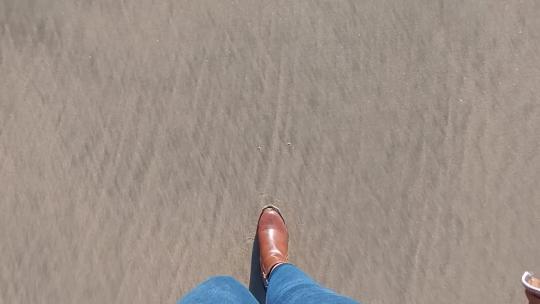 穿着靴子走在沙滩上