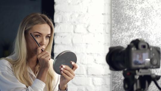 美女用镜子在相机上画眉毛视频素材模板下载