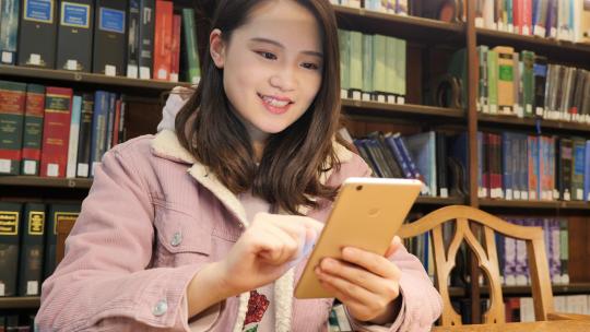 女留学生在图书馆使用电子设备学习
