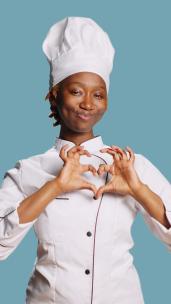 垂直视频女厨师在相机上显示心形符号