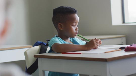 男孩坐在教室的桌子前
