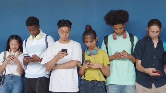 青少年在蓝墙上用智能手机聊天