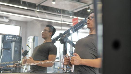男子在健身房使用划船器锻炼背部肌肉视频素材模板下载