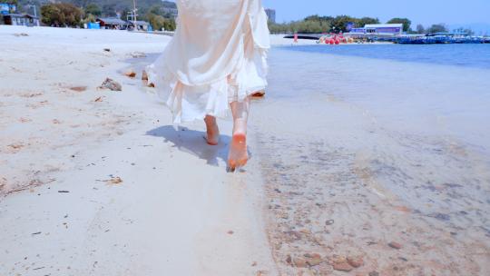 海边沙滩上光着脚丫行走在浅滩的姑娘