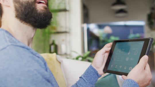 快乐的高加索男子在家中平板电脑上使用智能家居界面的视频