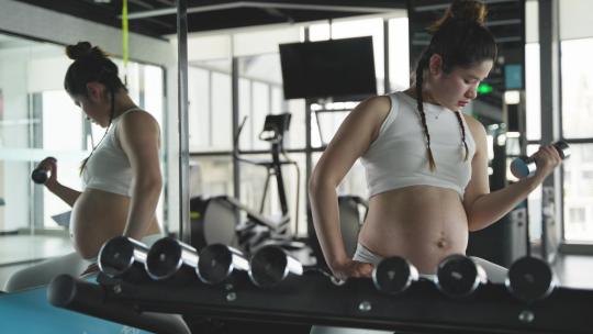 怀孕的妇女在健身房锻炼身体撸铁举哑铃