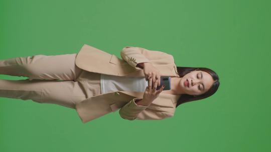 亚洲商务女性使用手机和走在绿屏色度键上