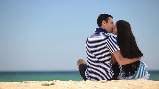 一对年轻夫妇坐在沙滩上
