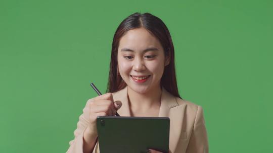 亚洲女商人在工作室的绿屏背景上写平板电脑的特写镜头