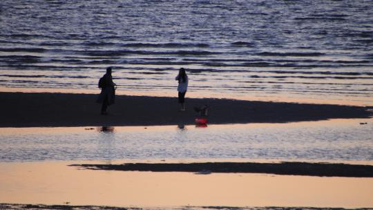 海边沙滩上拍照游玩的男女情侣