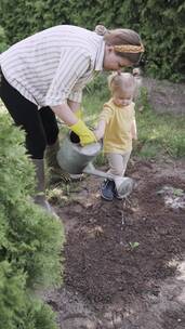 一个女人和小孩在给新种的植物浇水
