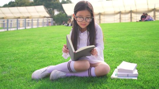 坐在草坪认真看书的小女孩