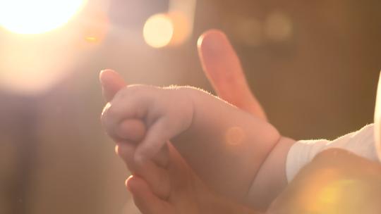 婴儿的小手拉着妈妈的手逆光拍摄