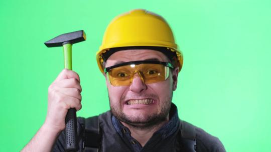 建筑工人用锤子敲他的安全帽