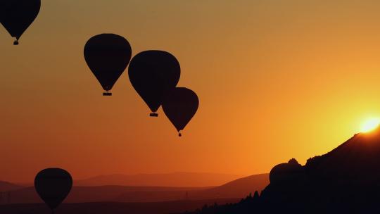 热气球在充满活力的橙色日落天空中飞行