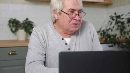 严肃老人盯着笔记本电脑屏幕发表演讲导语在线对话