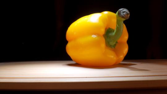 木质桌子上一个新鲜的黄色甜椒