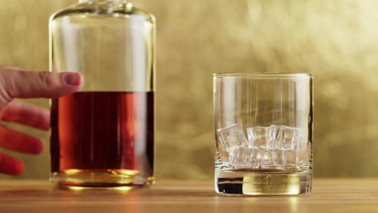 将瓶中威士忌倒入玻璃杯中的特写镜头
