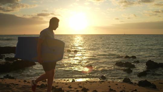 男人拿着冲浪板走在沙滩上视频素材模板下载