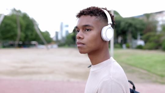 西班牙裔拉丁青少年男孩一边听音乐一边在户外散步视频素材模板下载