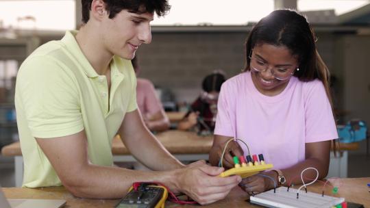 多元化的年轻学生在技术课上学习电子产品