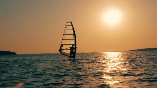 夕阳下在海上玩帆板的人无所畏惧