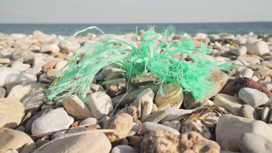 一根塑料绳子在沙滩上的卵石岩石上