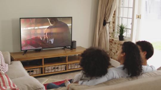 一家坐在沙发上看电视
