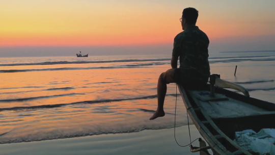 男生孤独坐在海边小船上  孤独 寂寞视频素材模板下载