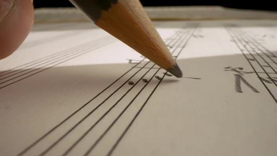 特写用铅笔在乐谱纸上谱写乐曲