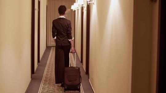 女人带着手提箱走在酒店走廊