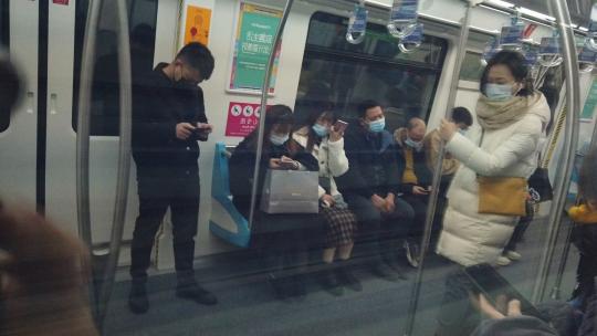 地铁玻璃反光玩手机的人
