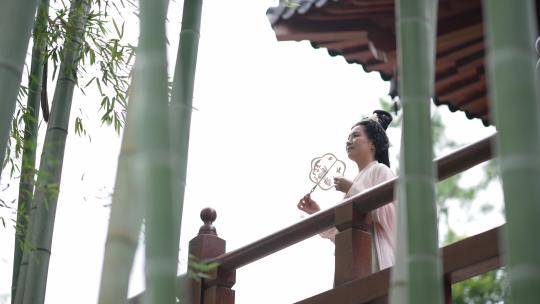 古装美女在竹林中的古建筑扇扇子
