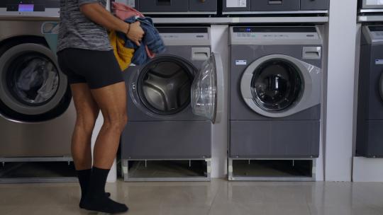 年轻的多种族男人穿着内衣在洗衣店洗衣服。