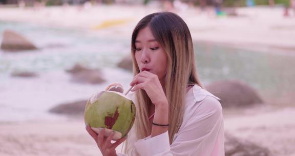 女孩在海边放松的喝椰汁