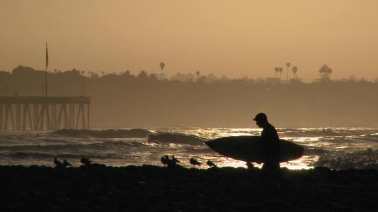 在夕阳下冲浪的男人剪影