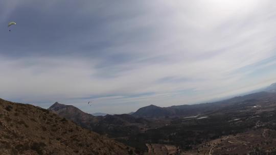 4K滑翔伞运动飞行在蓝天白云草地树林间