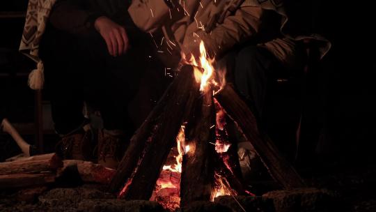 一家人户外露营坐在篝火旁取暖