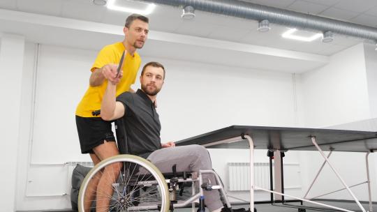 坐轮椅的人和一名教练训练乒乓球