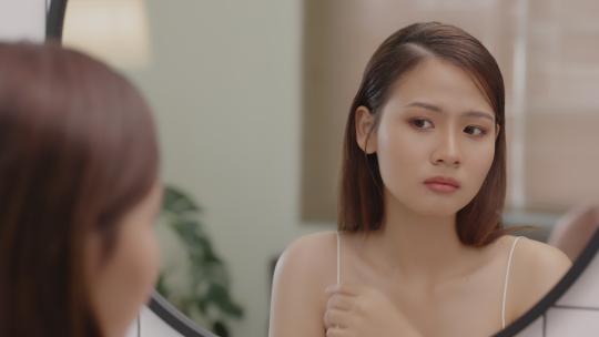 年轻亚洲女人看着镜子里的脸
