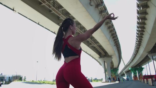 一名穿着红色训练服的成年女子站在桥下摆出漂亮的身体