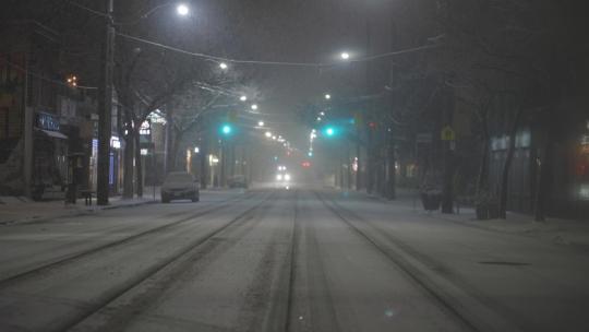 大雪漂泊的夜晚大雪中行驶的汽车街道道路